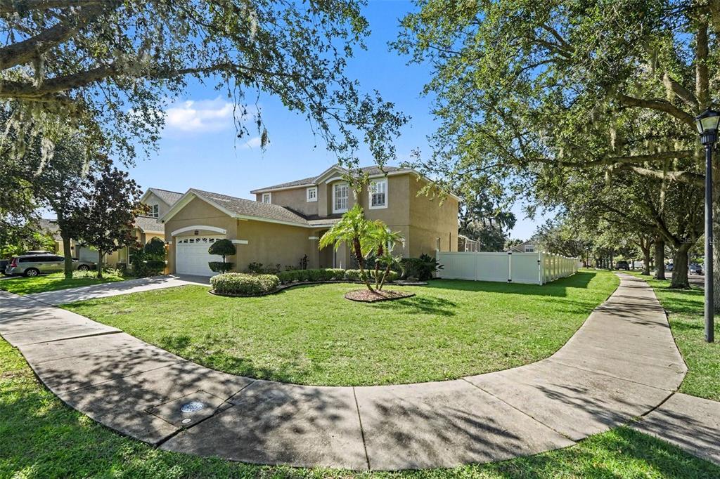 A two-story tan house with a two-car garage sits on a corner lot with sidewalks — 301 FERN GULLEY DRIVE, SEFFNER, FL