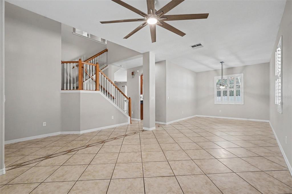 A spacious room with light tile flooring, a wooden staircase, and a ceiling fan — 301 FERN GULLEY DRIVE, SEFFNER, FL