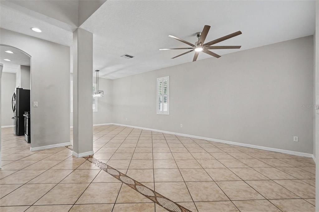 An open-concept living and dining area features light gray walls and diagonal tan floor tiles — 301 FERN GULLEY DRIVE, SEFFNER, FL
