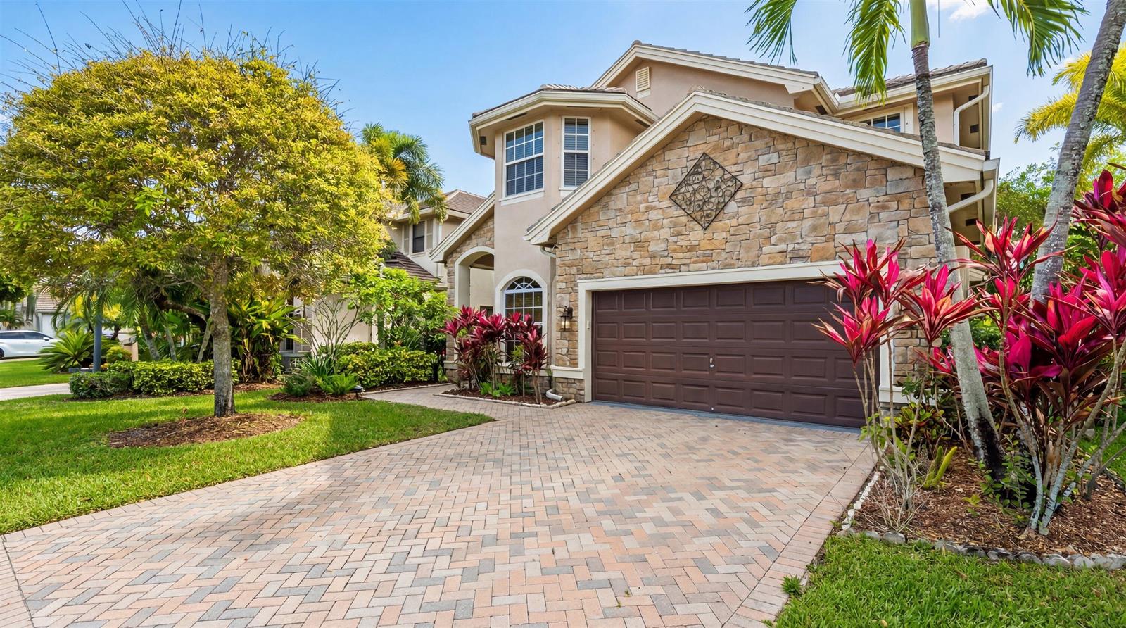 A two-story house with a stone facade, brown garage door, and a brick paver driveway — 3580 Birague Drive, Wellington FL 33449, WELLINGTON, FL