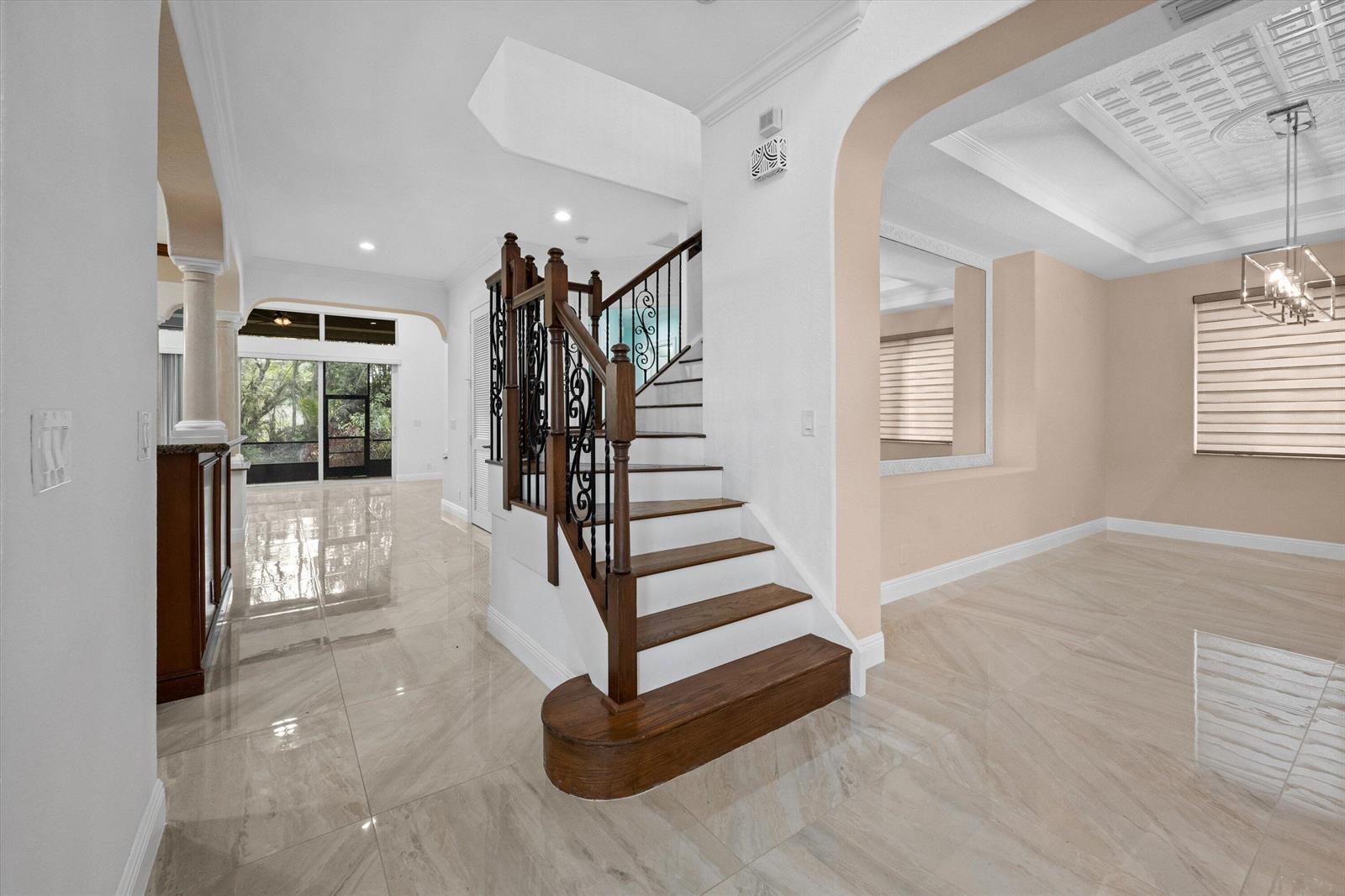 A staircase with wooden treads and iron railings stands in a room with tiled floors — 3580 Birague Drive, Wellington FL 33449, WELLINGTON, FL