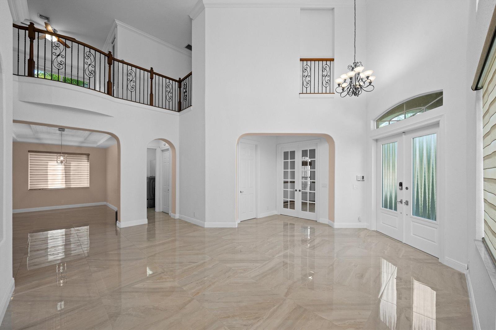 A spacious, high-ceilinged foyer features polished tile floors, a grand staircase, and double entry doors — 3580 Birague Drive, Wellington FL 33449, WELLINGTON, FL