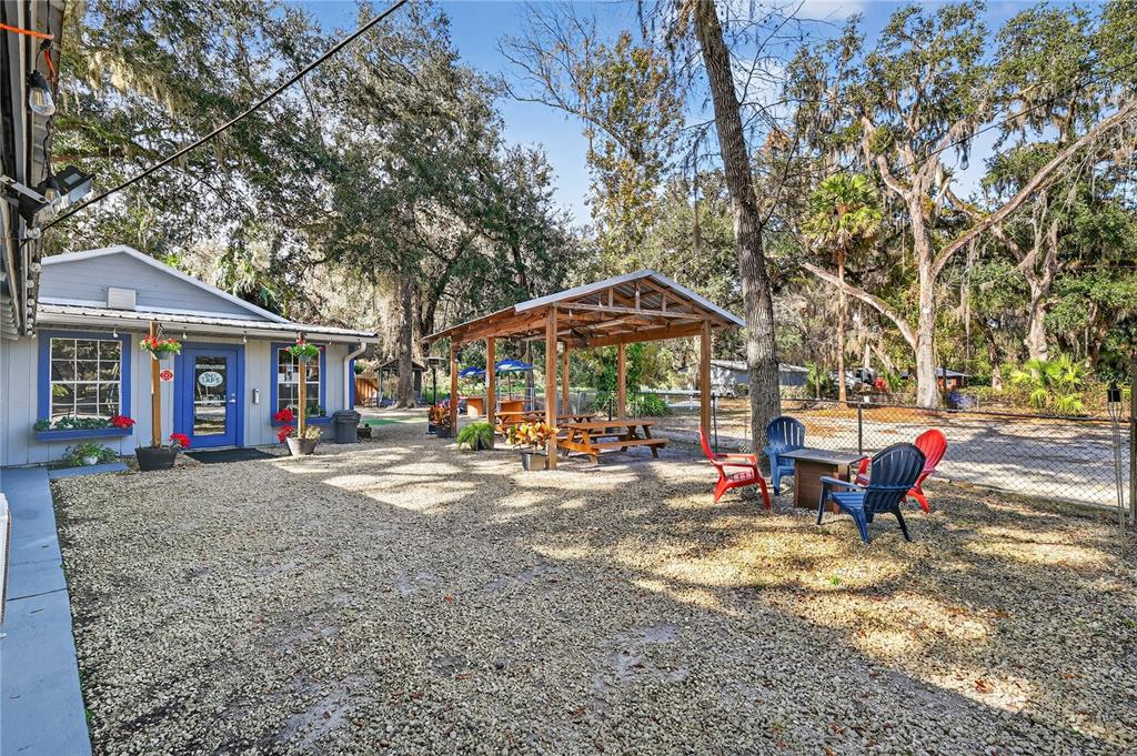 An outdoor patio area features a gravel ground, a wooden pavilion, and several chairs — 2396 N C 470, LAKE PANASOFFKEE, FL