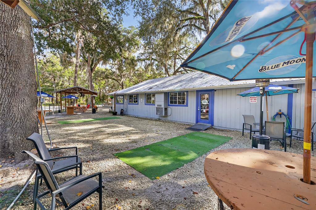 An outdoor patio area features gravel, artificial turf, patio furniture, and a Blue Moon umbrella — 2396 N C 470, LAKE PANASOFFKEE, FL