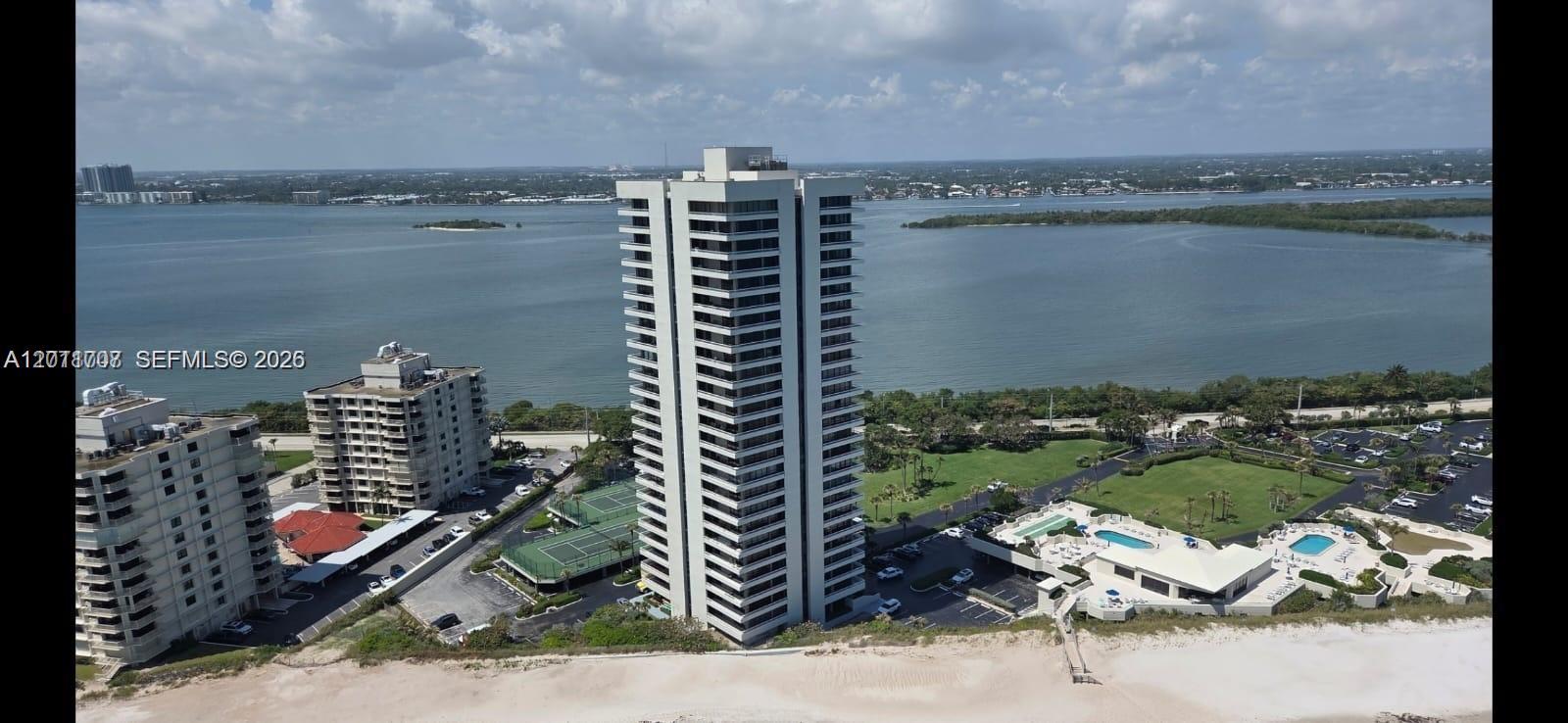 An aerial view shows a tall residential building on a beach near a bay — 5510 N Ocean Dr # 19B, Singer Island FL 33404, SINGER ISLAND, FL