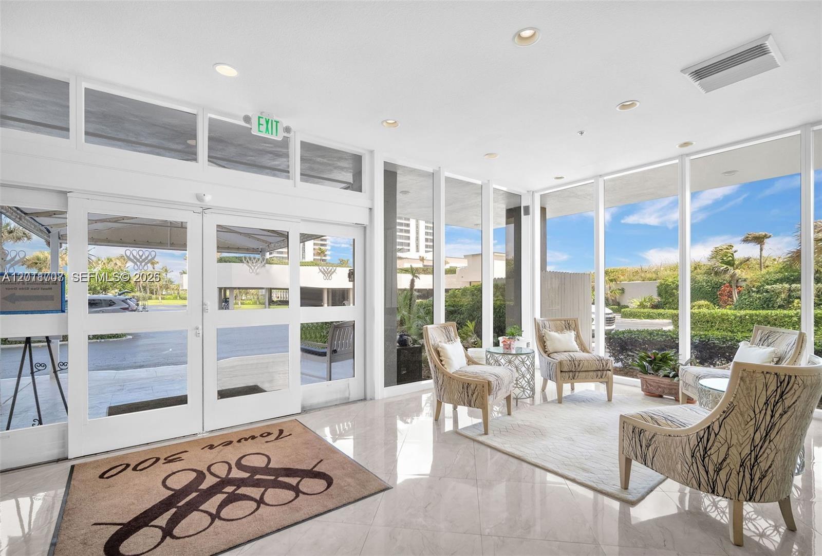 A bright lobby features floor-to-ceiling windows, patterned armchairs, and a branded floor mat — 5510 N Ocean Dr # 19B, Singer Island FL 33404, SINGER ISLAND, FL