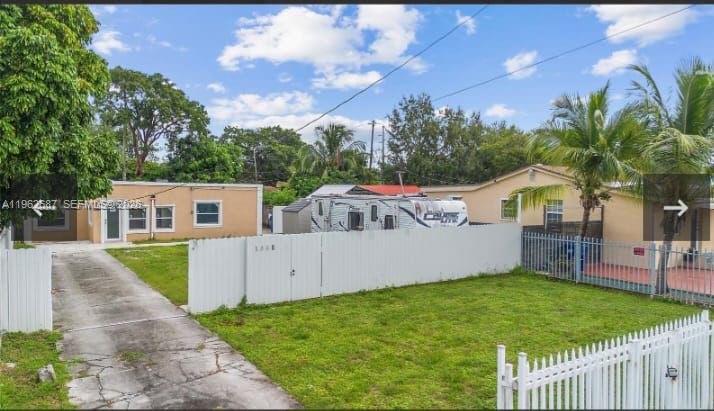 An exterior view of a single-story house with a driveway, a white fence, and a trailer — 1835 NW 85th St, Miami FL 33147, MIAMI, FL