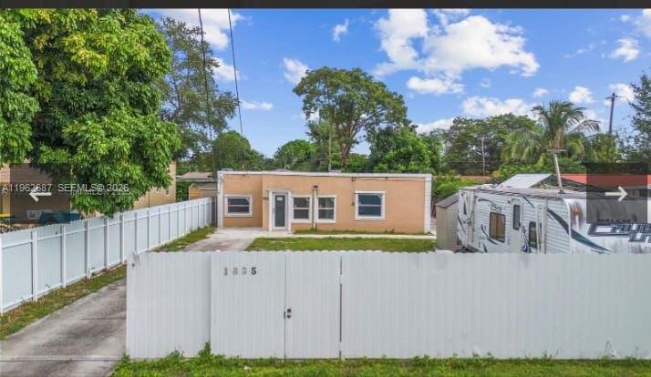 A single-story tan house sits behind a white vinyl fence with a parked camper trailer — 1835 NW 85th St, Miami FL 33147, MIAMI, FL