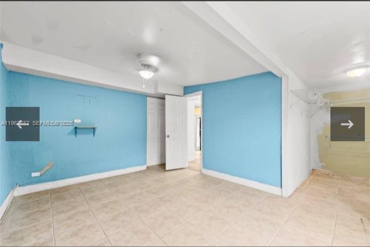 An empty room with light blue walls, beige tile flooring, and a white ceiling fan — 1835 NW 85th St, Miami FL 33147, MIAMI, FL