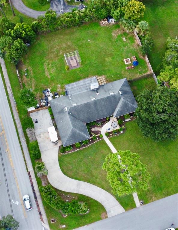An aerial view shows a house with a large backyard, driveway, and surrounding greenery — 1200 WAVERLY WAY, LONGWOOD, FL