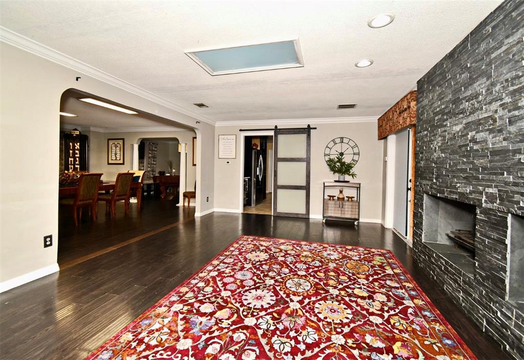 A living room features a dark stone fireplace, a large red patterned rug, and dark flooring — 1200 WAVERLY WAY, LONGWOOD, FL
