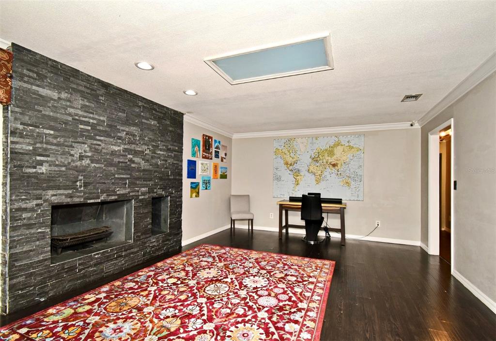 A room features a dark stone fireplace, a world map wall art, and a patterned rug — 1200 WAVERLY WAY, LONGWOOD, FL