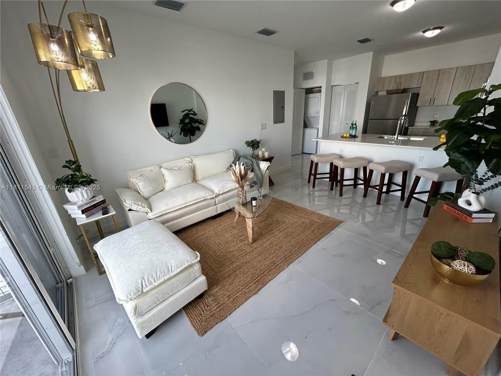 A bright living room and kitchen area features white tile floors, a sofa, and bar stools — 1010 SW 69th Ave # 104, Miami FL 33144, MIAMI, FL
