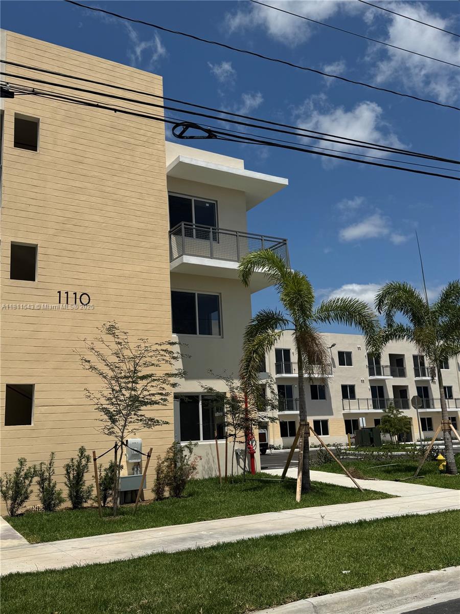 A multi-story apartment building with a beige facade, balconies, and palm trees on a sunny day — 1010 SW 69th Ave # 104, Miami FL 33144, MIAMI, FL