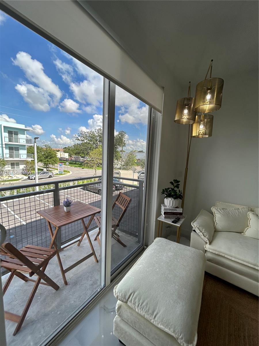 A living room with a white sofa and ottoman overlooks a balcony with outdoor furniture — 1010 SW 69th Ave # 104, Miami FL 33144, MIAMI, FL