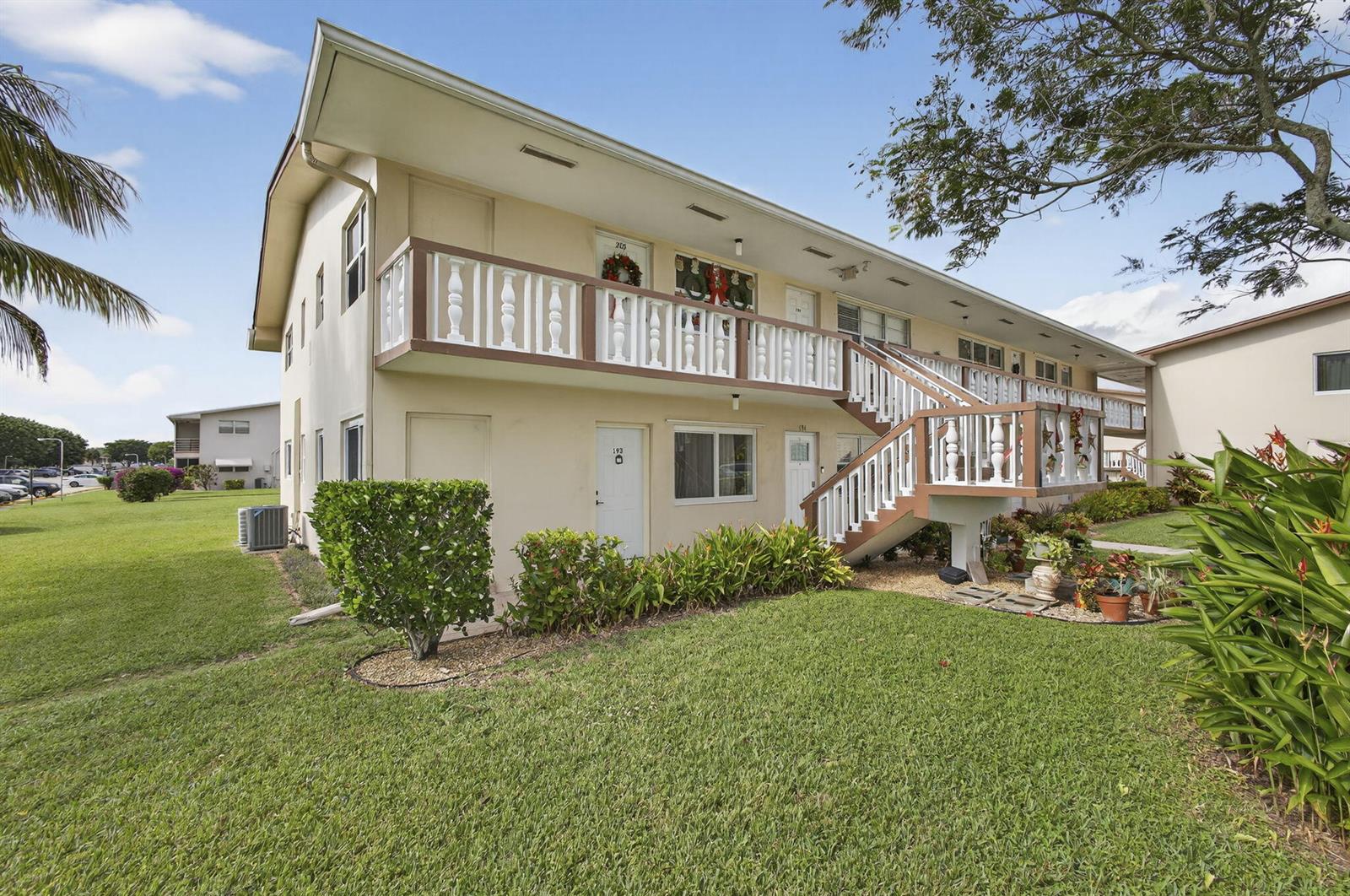 A two-story apartment building features a white exterior, a wooden staircase, and a balcony — 193 Easthampton I, West Palm Beach FL 33417, WEST PALM BEACH, FL