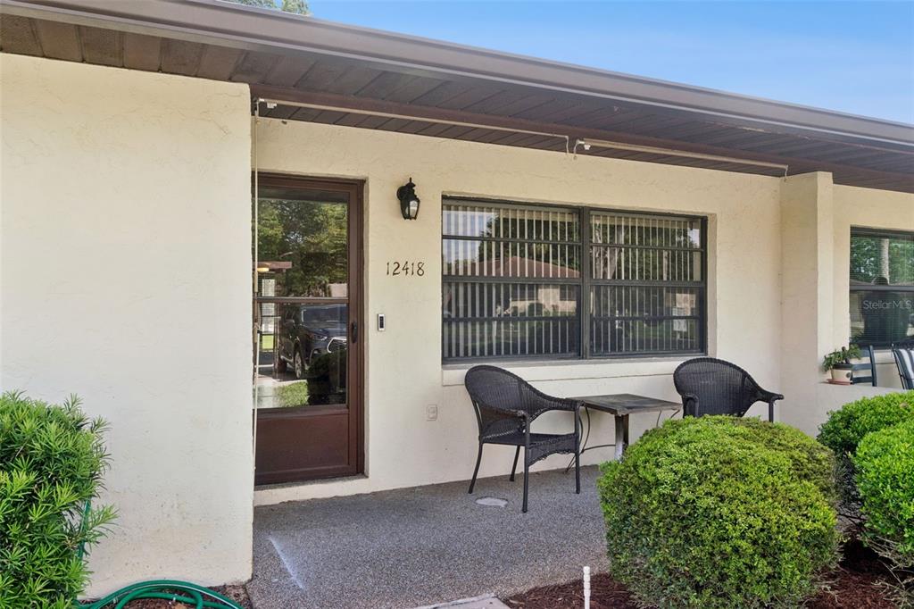 A front exterior view shows a patio with two chairs, a table, and a door — 12418 ORANGEWOOD CIRCLE, TAVARES, FL