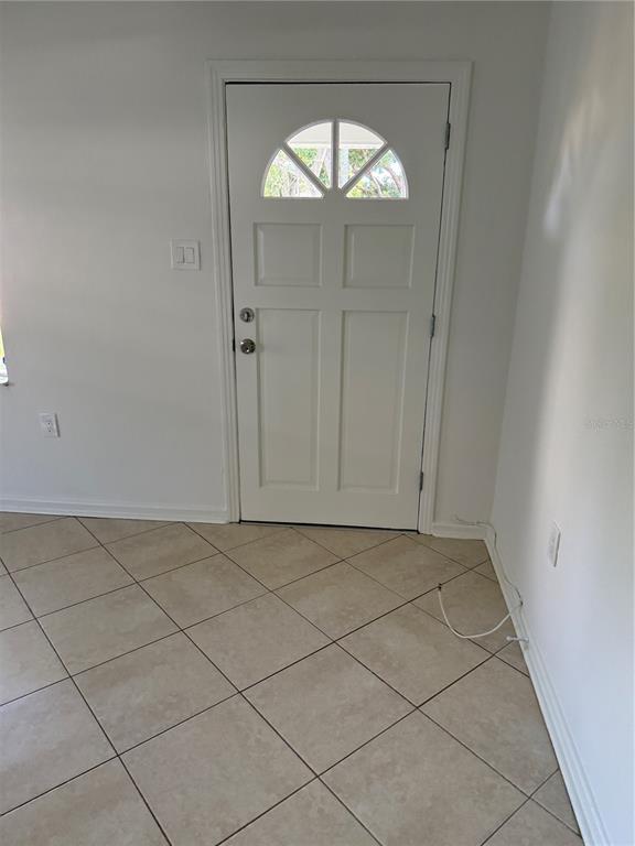 A white front door with a semi-circular window sits in a room with tiled flooring — 1317 35TH AVENUE N, ST PETERSBURG, FL