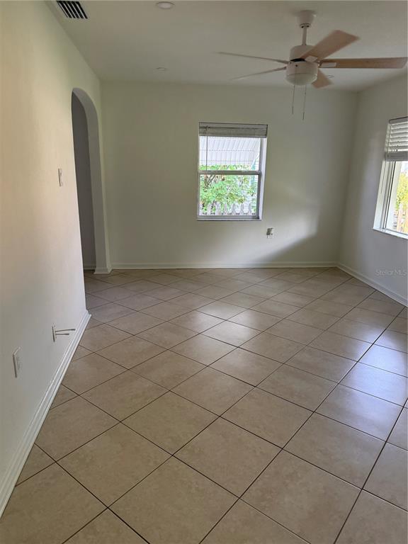 An empty room with beige tile flooring, a ceiling fan, and two windows — 1317 35TH AVENUE N, ST PETERSBURG, FL