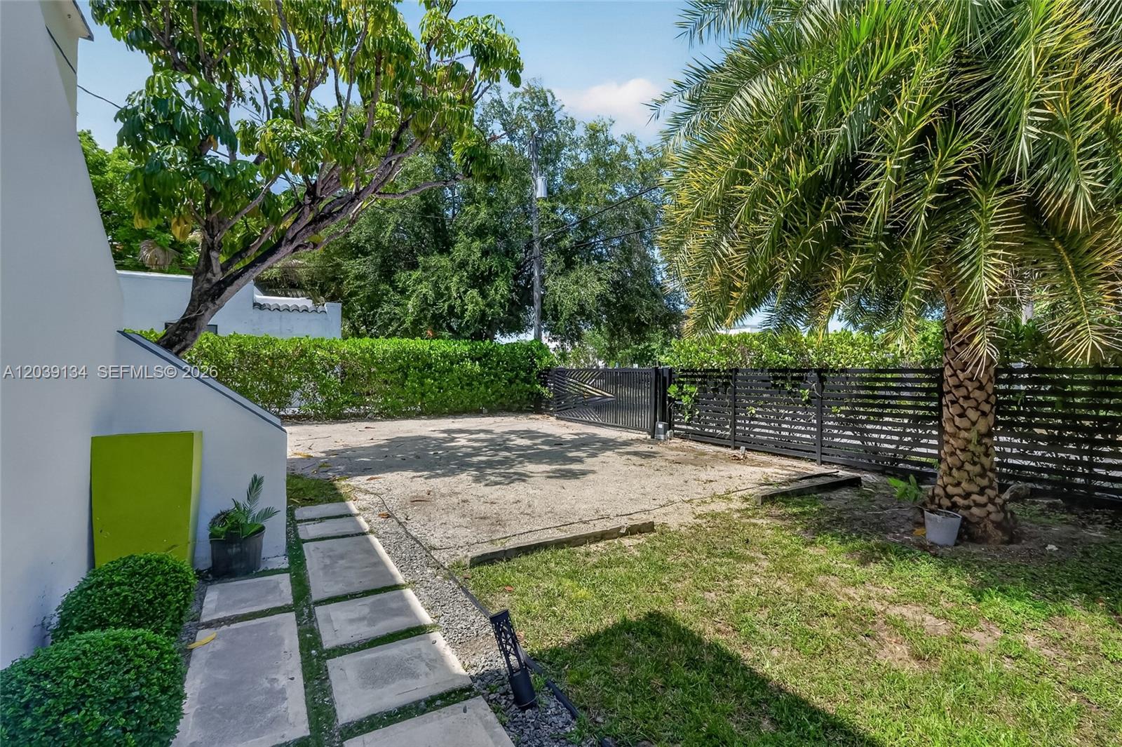 A paved driveway leads to a black metal gate in a fenced backyard with landscaping — 8270 NE 1st Pl # 3, Miami FL 33138, MIAMI, FL