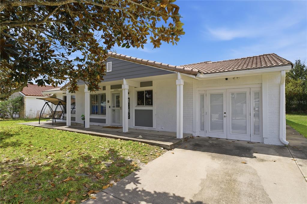 A single-story house with a white brick exterior, a covered porch, and a concrete driveway — 10725 WILLIAM TELL DRIVE, ORLANDO, FL