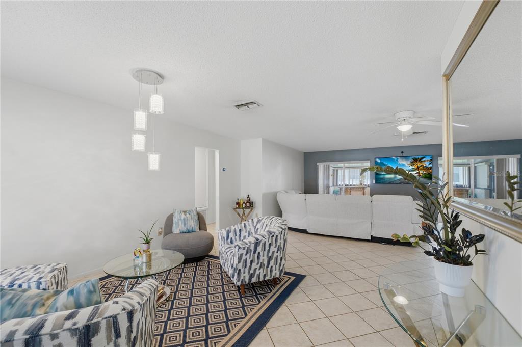A living room features tile floors, a patterned area rug, and a white sectional sofa — 10725 WILLIAM TELL DRIVE, ORLANDO, FL