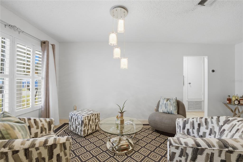 A living room features patterned armchairs, a glass coffee table, and a modern pendant light — 10725 WILLIAM TELL DRIVE, ORLANDO, FL