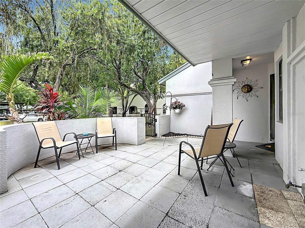 A paved patio features four outdoor chairs, a small table, and a sun wall decoration — 3873 PHEASANT COURT, PALM HARBOR, FL