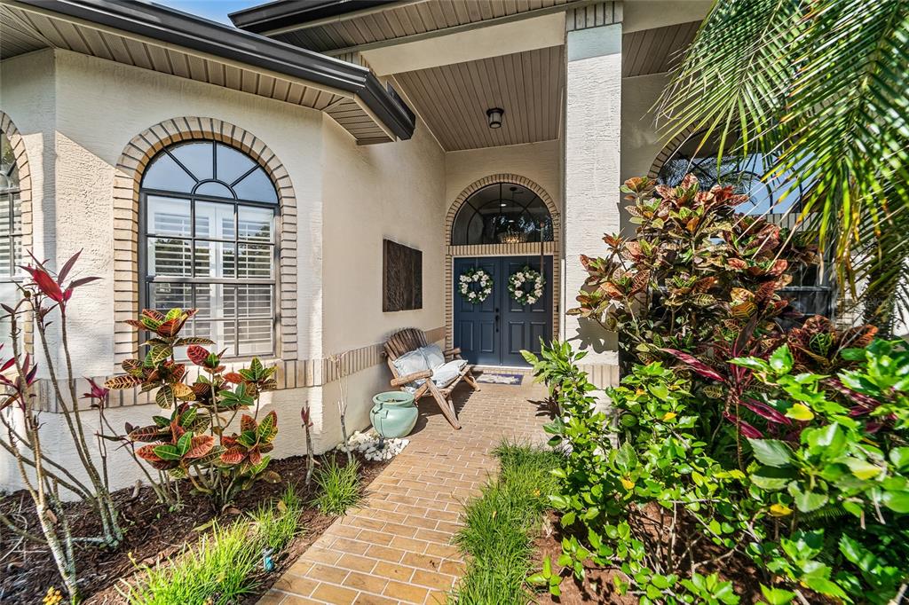 The exterior of a house features a brick walkway leading to a double front door — 1012 KINGSBOROUGH GARDENS COURT, LUTZ, FL