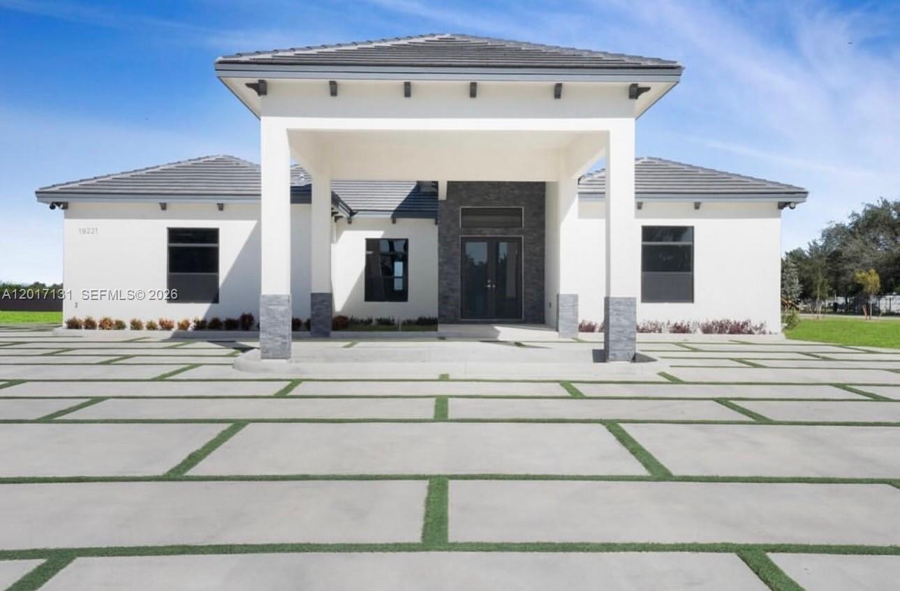 A modern single-story house features a large covered entryway and a concrete paver driveway — sw 246 sw 187 Ave, Miami FL 33031, MIAMI, FL