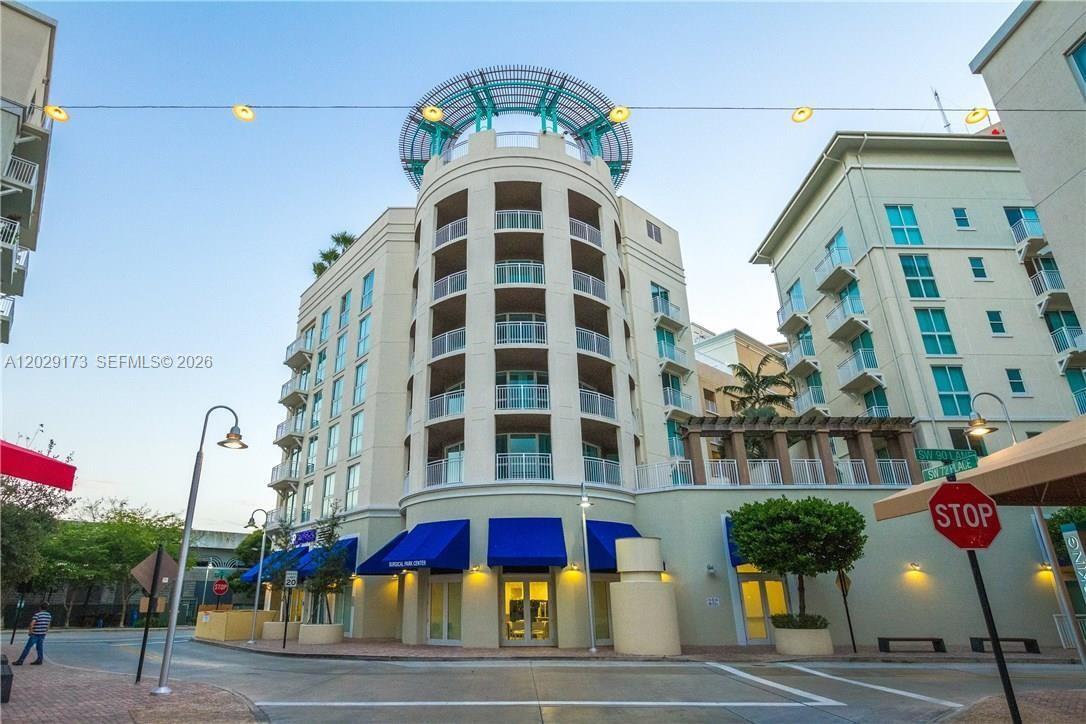 A multi-story building with a curved facade, blue awnings, and a decorative rooftop structure — 7270 SW 88th St # B502, Miami FL 33156, MIAMI, FL