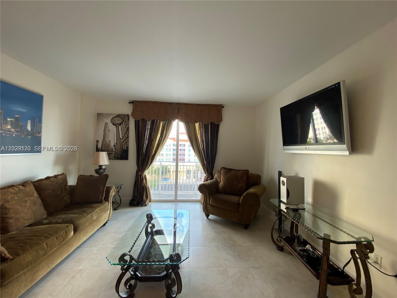 A living room features a brown sofa, an armchair, a glass coffee table, and a television — 7270 SW 88th St # B502, Miami FL 33156, MIAMI, FL