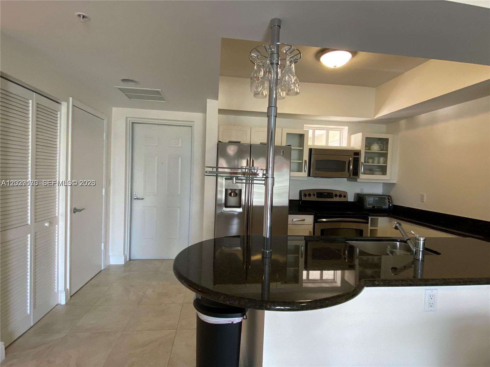 A kitchen features dark granite countertops, stainless steel appliances, and a central glass-topped breakfast bar — 7270 SW 88th St # B502, Miami FL 33156, MIAMI, FL