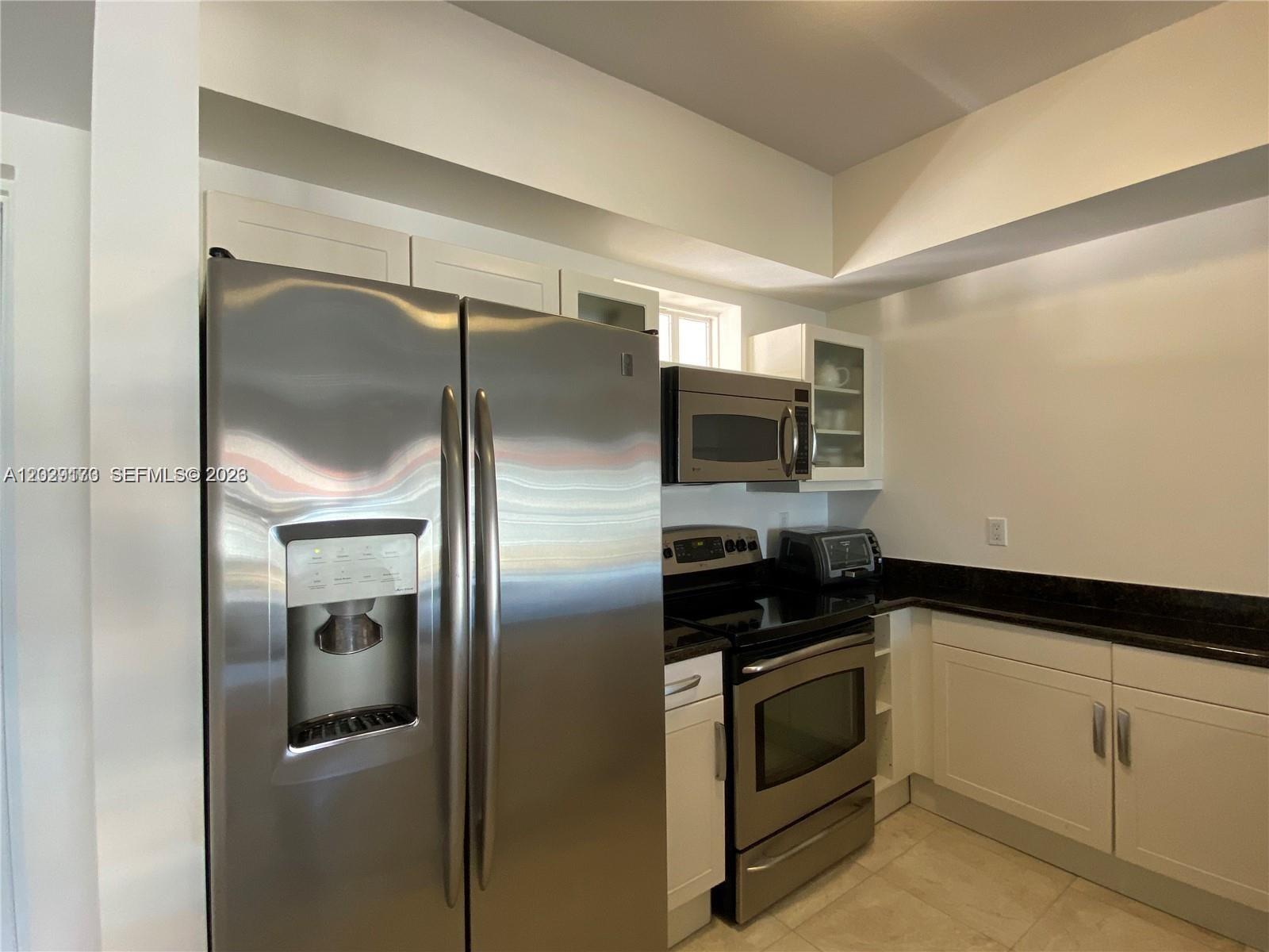 A kitchen features stainless steel appliances, white cabinetry, and dark countertops — 7270 SW 88th St # B502, Miami FL 33156, MIAMI, FL