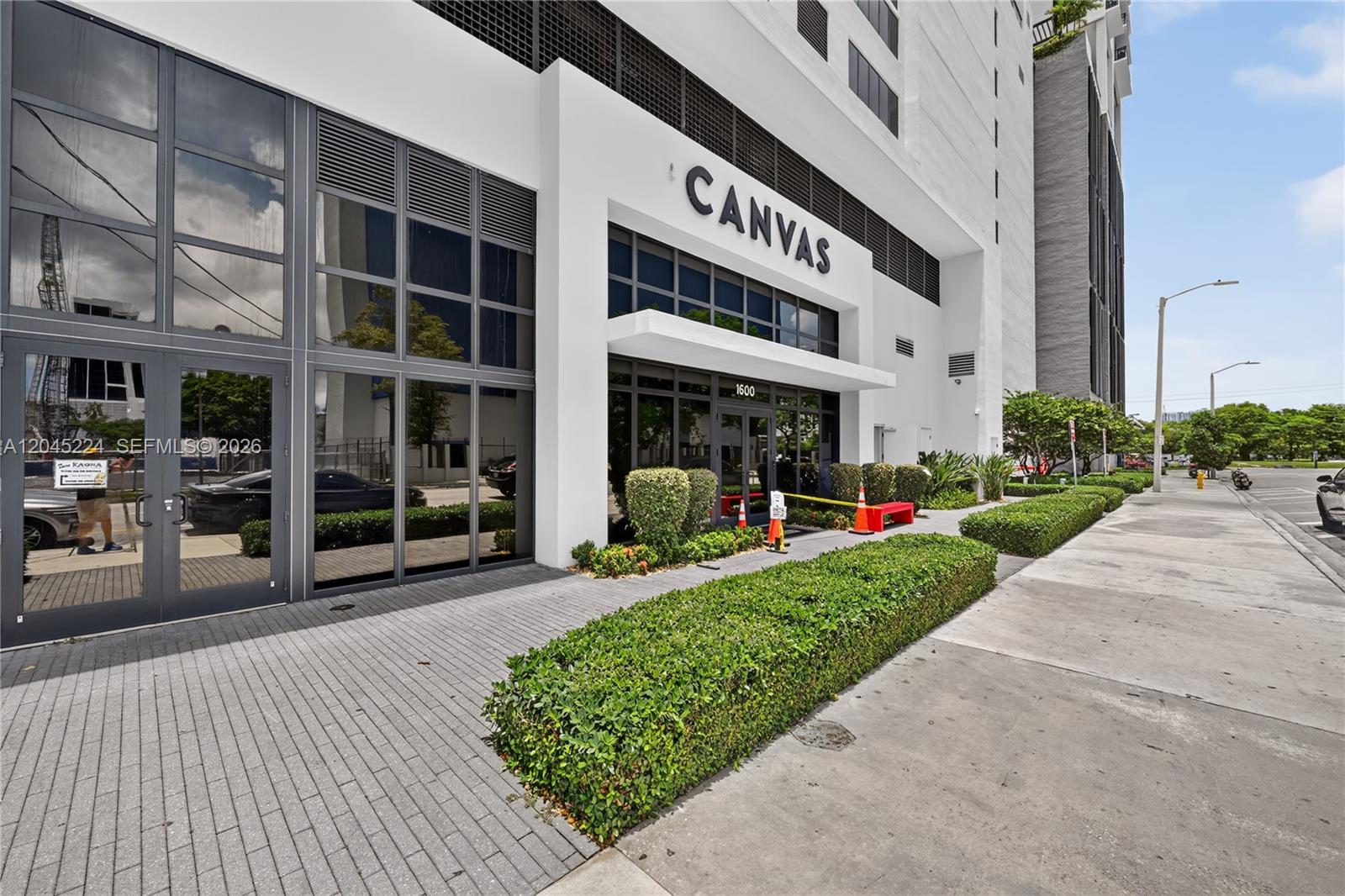 The exterior of a modern white building features large glass windows and a prominent entrance sign — 1600 NE 1st Ave # 1210, Miami FL 33132, MIAMI, FL