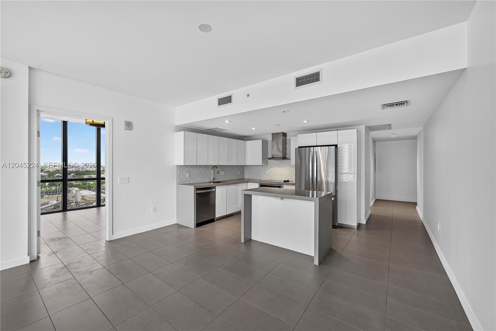 A modern kitchen features white cabinets, stainless steel appliances, a center island, and tile flooring — 1600 NE 1st Ave # 1210, Miami FL 33132, MIAMI, FL