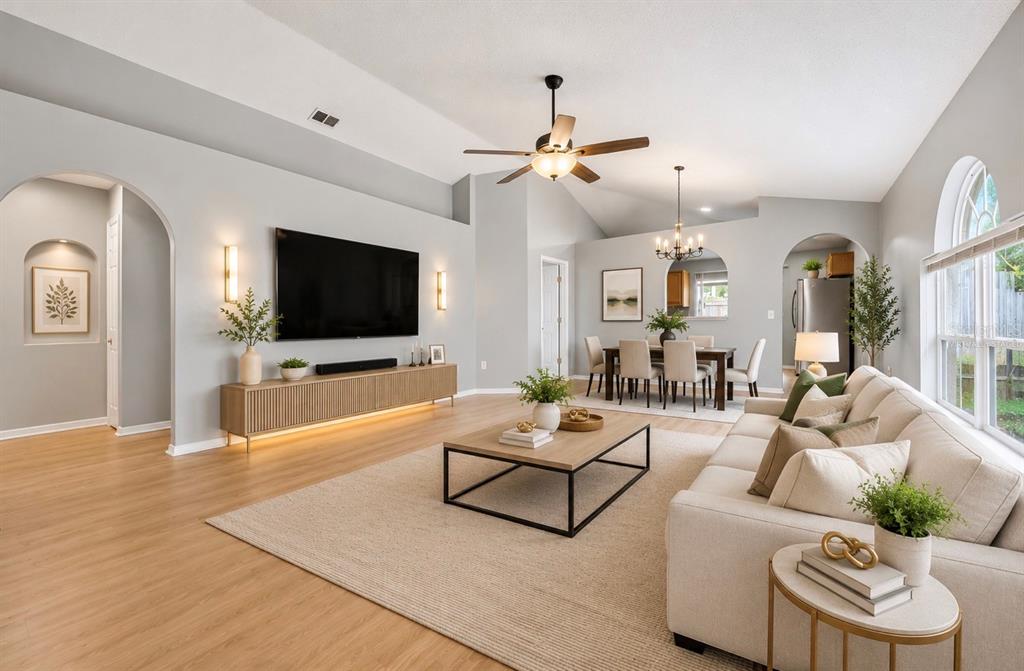 A bright living room features light wood flooring, a large television, and an adjacent dining area — 10617 OPUS DRIVE, RIVERVIEW, FL