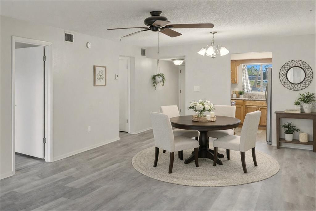 A dining area features a round table with four chairs on a circular rug — 3531 LAKE BAYSHORE DRIVE UNIT J106, BRADENTON, FL