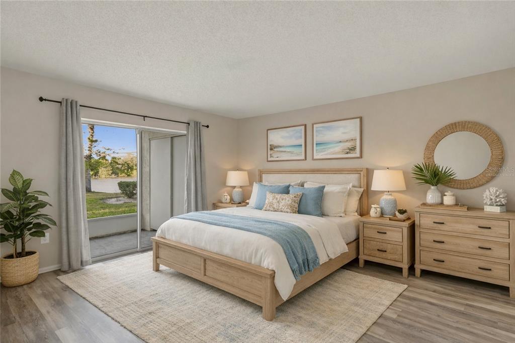 A bedroom features a wooden bed, matching dresser, and a sliding glass door to a patio — 3531 LAKE BAYSHORE DRIVE UNIT J106, BRADENTON, FL