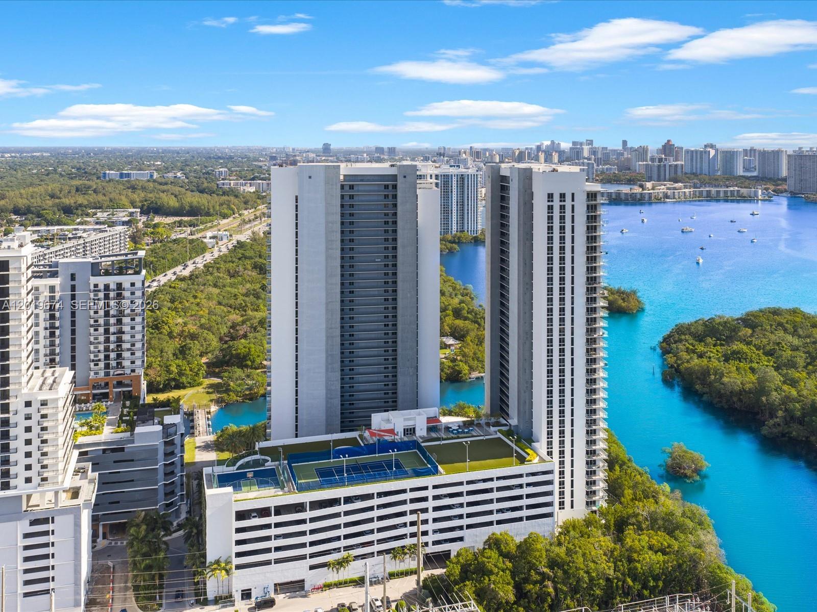 An aerial view shows two tall residential towers connected by a parking garage with rooftop courts — 16385 Biscayne Blvd # 3103, North Miami Beach FL 33160, NORTH MIAMI BEACH, FL