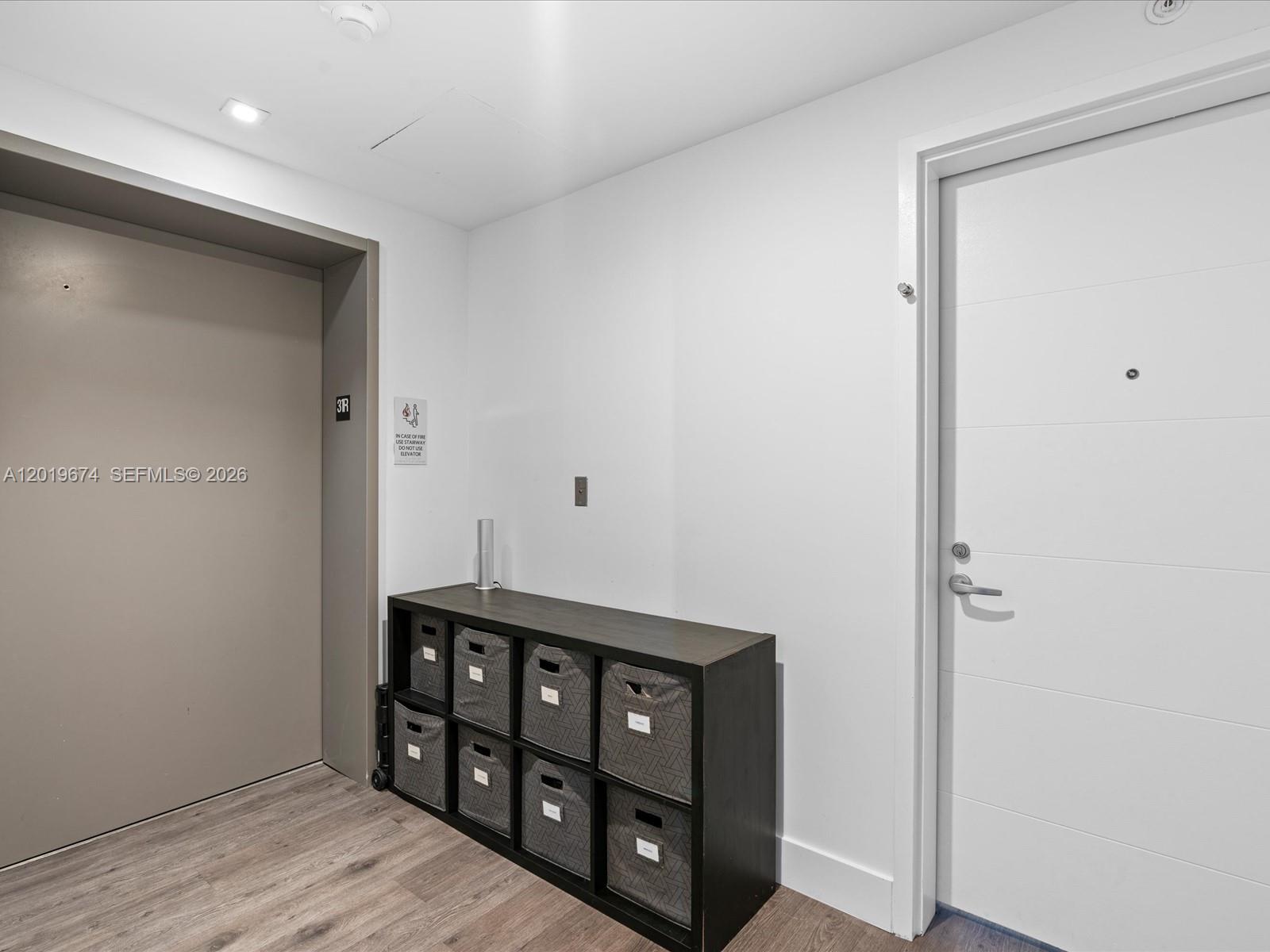 A hallway features a dark storage unit with fabric bins, wood flooring, and two doors — 16385 Biscayne Blvd # 3103, North Miami Beach FL 33160, NORTH MIAMI BEACH, FL