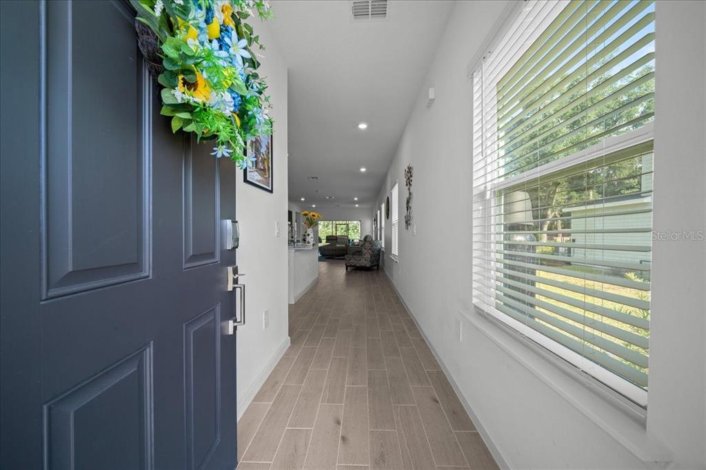 A view from an open front door into a hallway with light wood-look tile flooring — 3902 NE 30TH TERRACE, OCALA, FL