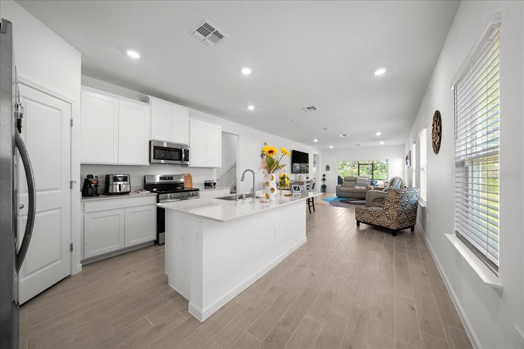 A modern kitchen with white cabinets and a central island opens into a living area — 3902 NE 30TH TERRACE, OCALA, FL
