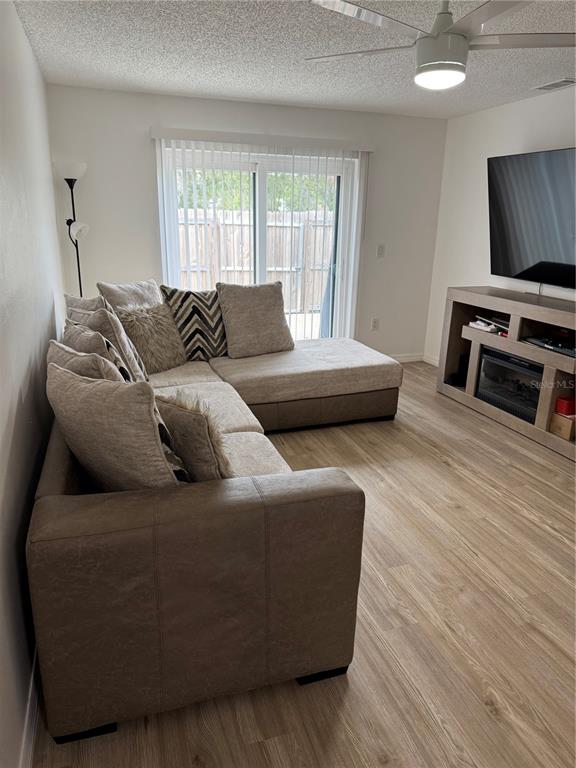 A living room features a sectional sofa, a television console, and light wood-look flooring — 2342 BARBADOS COURT, KISSIMMEE, FL