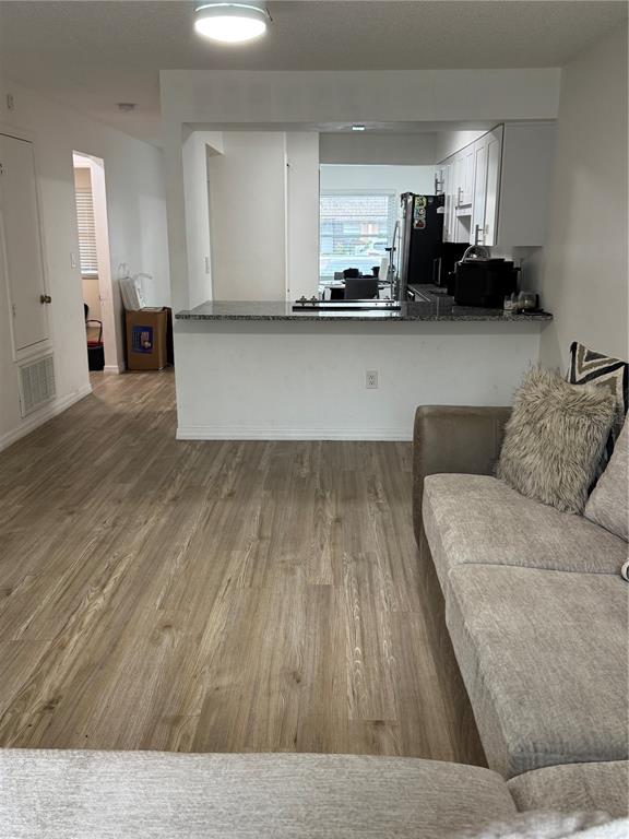 A living room with wood-look flooring opens to a kitchen featuring a granite breakfast bar — 2342 BARBADOS COURT, KISSIMMEE, FL