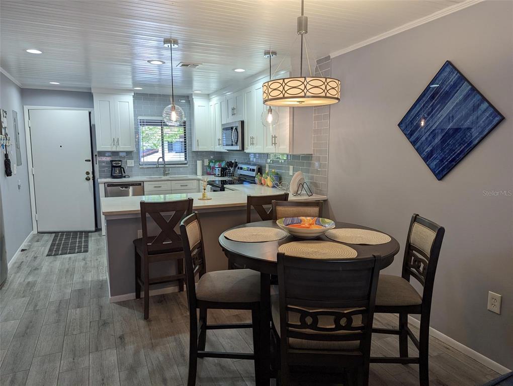 A kitchen with white cabinets and a dining area with a round table and chairs — 1634 STICKNEY POINT ROAD UNIT 1634-2, SARASOTA, FL