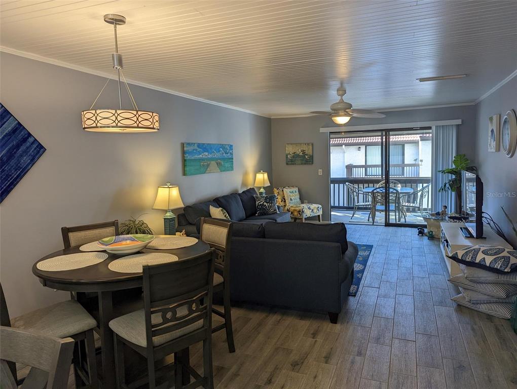 A living and dining area with wood-look tile floors, a dark sofa, and sliding glass doors — 1634 STICKNEY POINT ROAD UNIT 1634-2, SARASOTA, FL