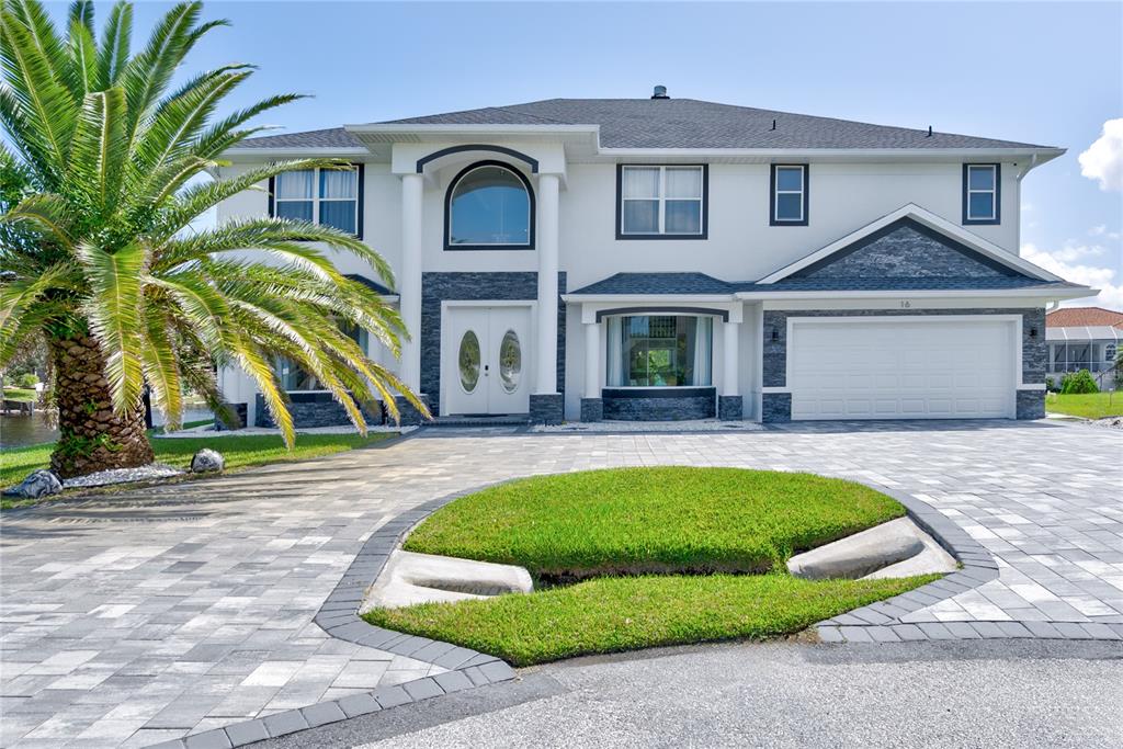 A two-story house with a white stucco exterior, stone accents, and a paved driveway — 16 FLORENCE COURT, PALM COAST, FL