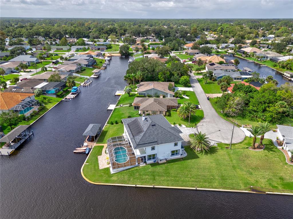 An aerial view shows a waterfront house with a pool, dock, and solar panels — 16 FLORENCE COURT, PALM COAST, FL