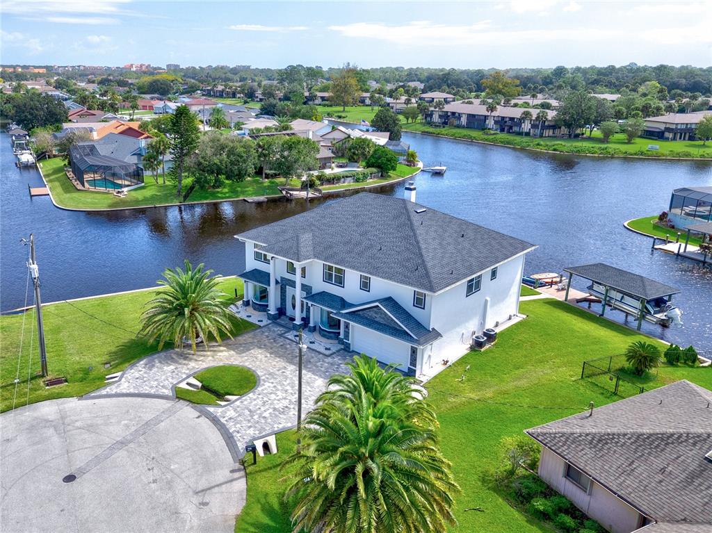 An aerial view shows a two-story white house with a dark roof beside a canal — 16 FLORENCE COURT, PALM COAST, FL